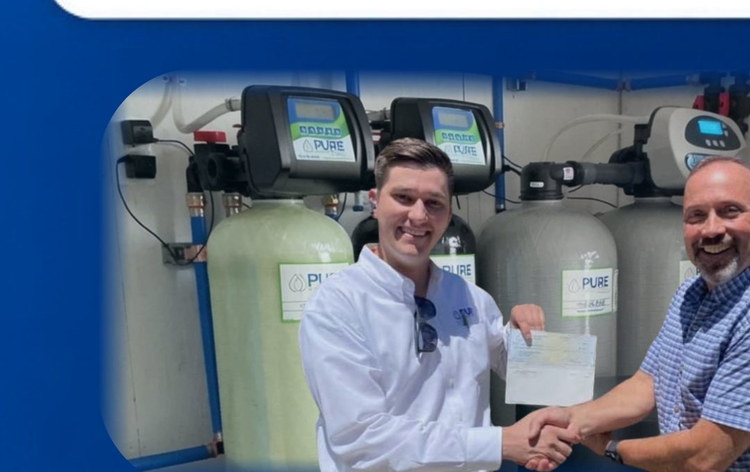 A Pure Water Systems technician shaking hands with a homeowner in front of installed tanks