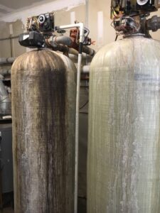 Original 15-year-old filtration tanks with leak staining and missing control valve covers